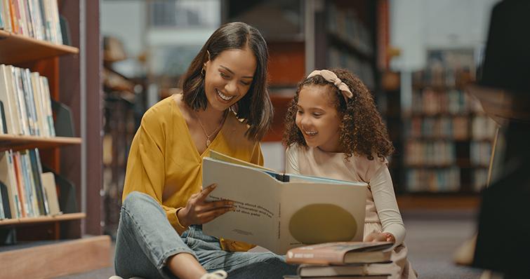 Mother and daughter reading together in library