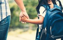 Child with a backpack holding a parent's hand